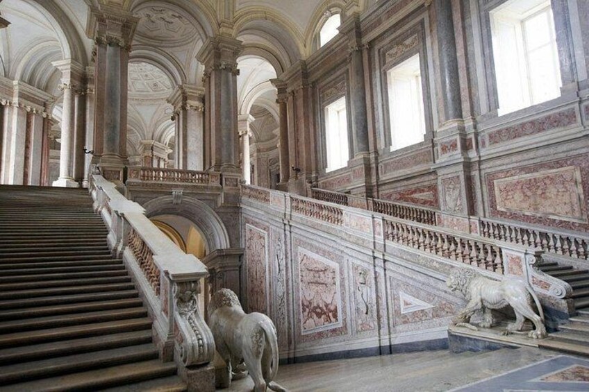 A grand staircase with ornate railings and a lion statue at the bottom. 5