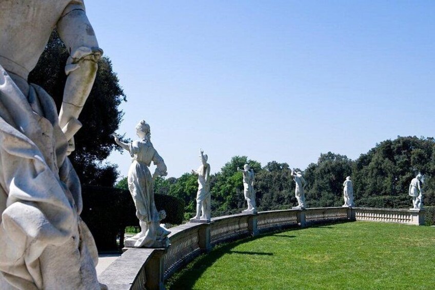A row of white statues on a curved pathway in a park. 4