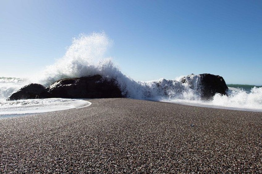 A pebbled beach with waves crashing against rocks. 3