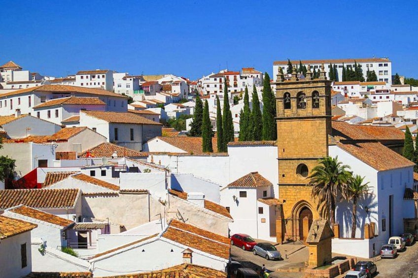 A coastal town with white buildings, a prominent tower, and a clear blue sky. 2