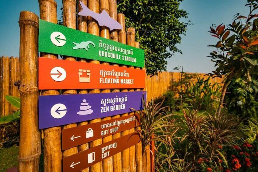 A directional signpost with multiple arrows pointing to various attractions such as a crocodile stadium, floating market, zen garden, gift shop, and exit. 3