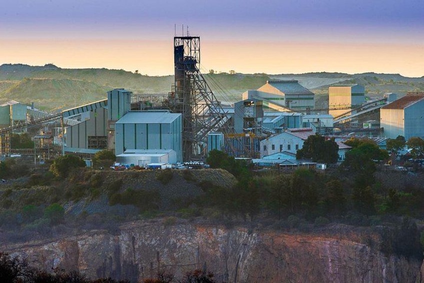 A mining facility with large buildings, a conveyor belt system, and a prominent tower structure. 2