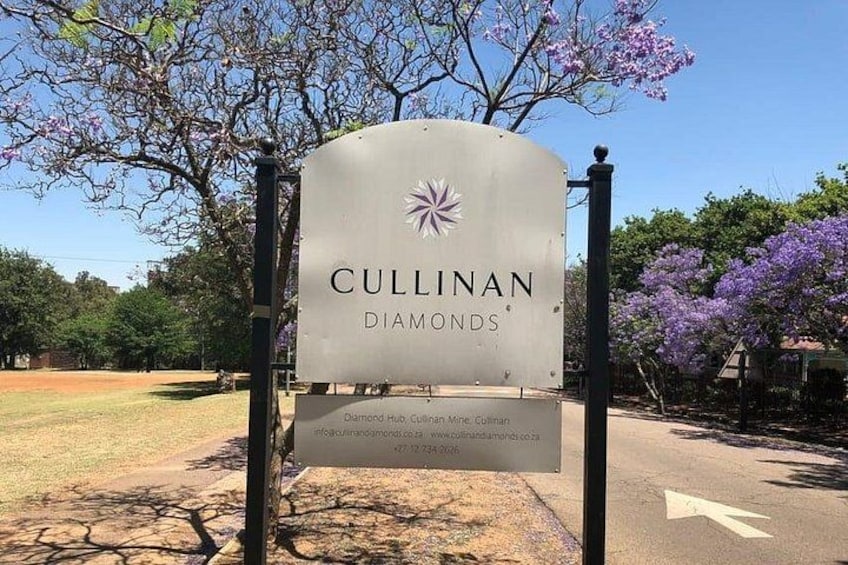 A sign for Cullinan Diamonds with a logo, a directional arrow, and a website URL. 3