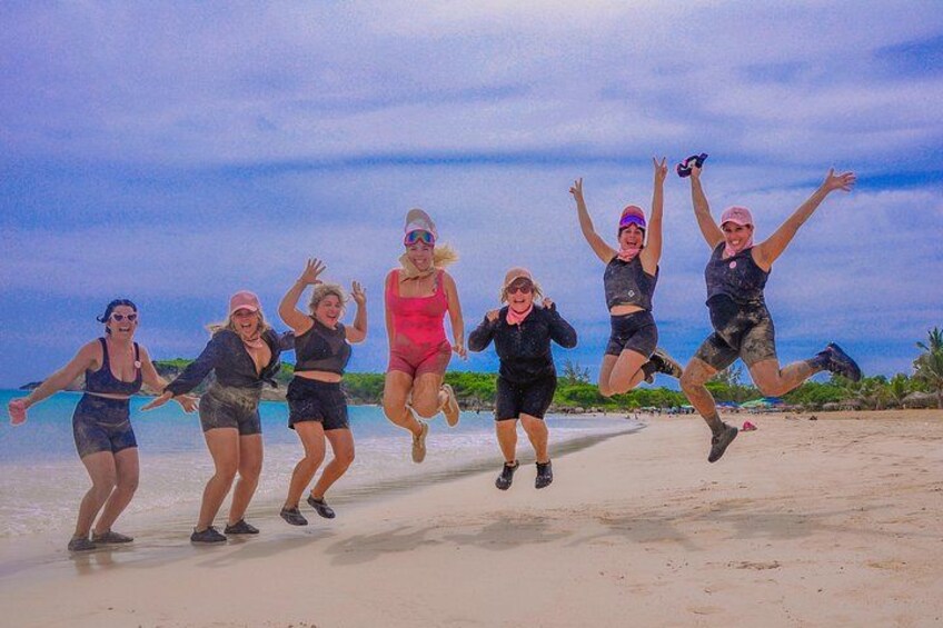 A group of people jumping on a beach with a clear sky and ocean in the background. 4