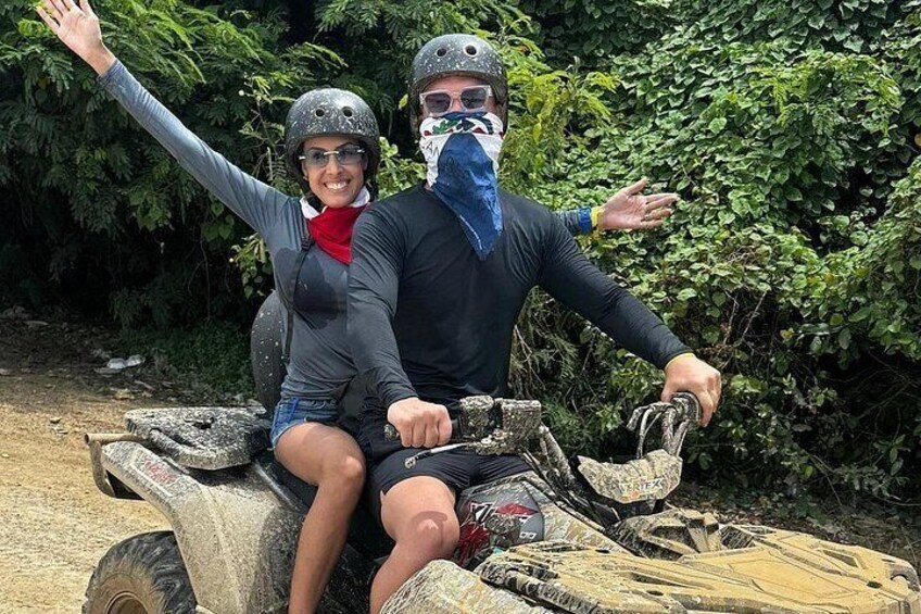 Two people on an ATV in a forested area. 5