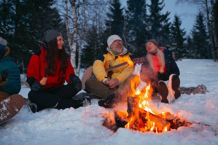 People sitting around a campfire in a snowy forest. 2