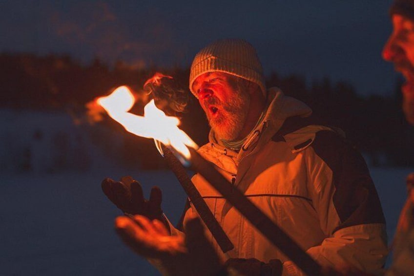 A person holding a flaming torch in a snowy landscape at night. 5