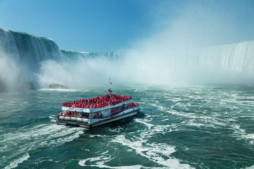 Een boot vol passagiers in het rood, een grote waterval en nevel in de lucht. 4