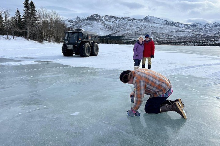 Une personne à genoux sur la glace, un véhicule et un paysage montagneux. 3