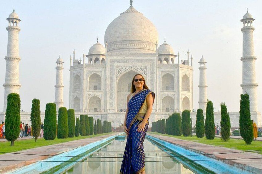 A person in a blue and gold sari standing in front of the Taj Mahal. 2