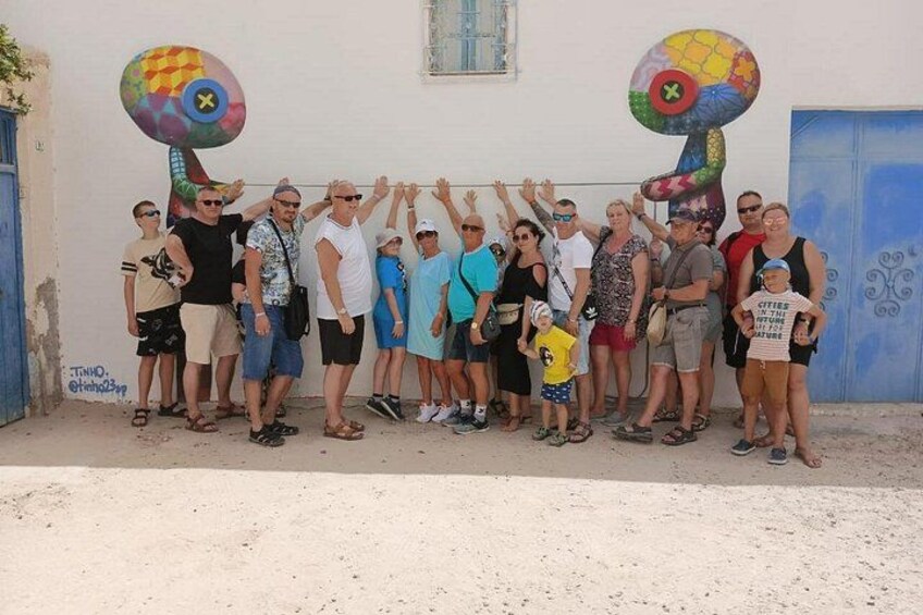 Un groupe de personnes posant devant un mur orné de peintures murales colorées. 5