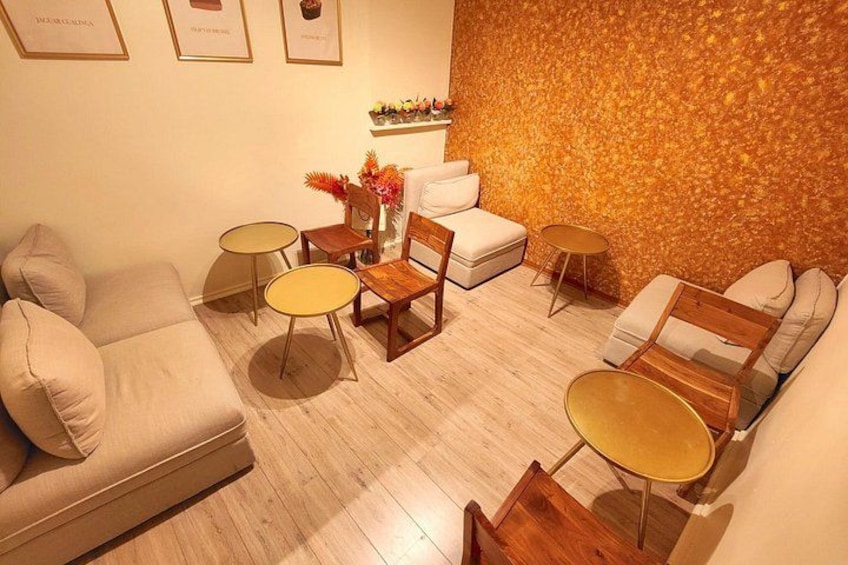 Een moderne woonkamer met een beige bank, twee fauteuils, een salontafel en een decoratieve wand. 3