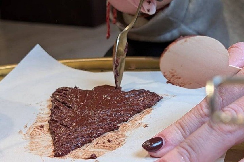 Iemand verdeelt chocolade over bakpapier. 2