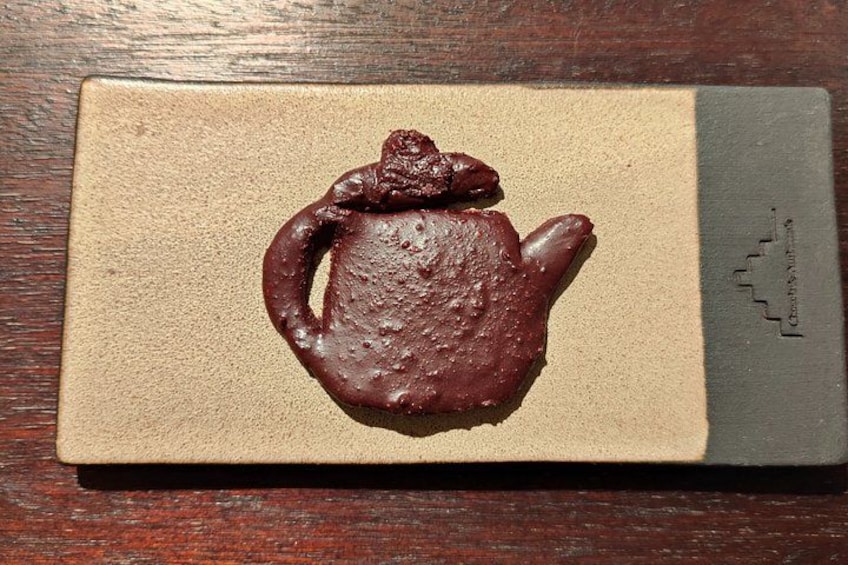 Een chocolade theepot op een beige doos met een logo. 2