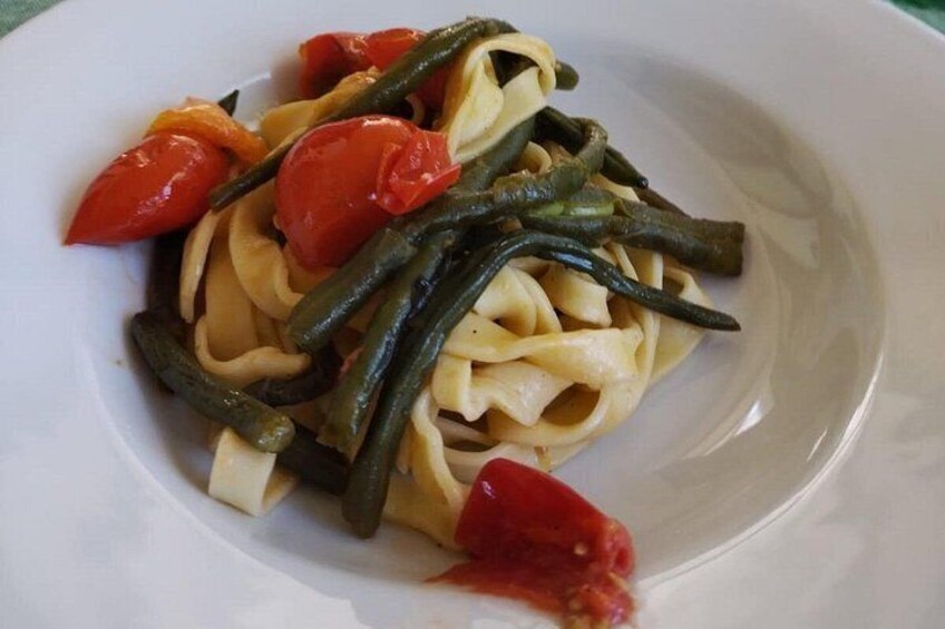 A plate of pasta with green beans and cherry tomatoes. 2