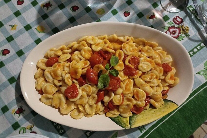 A bowl of pasta with cherry tomatoes and basil on a tablecloth with a checkered pattern. 5