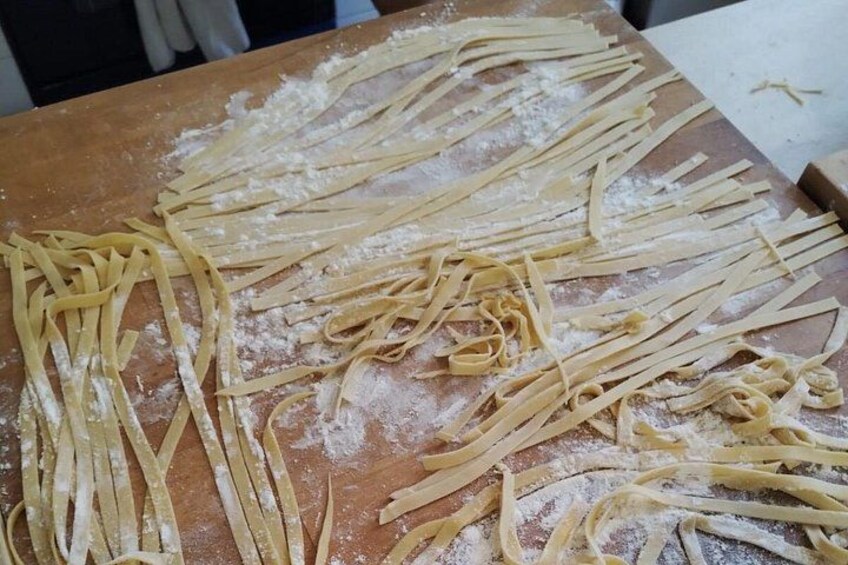 Uncooked pasta on a wooden surface with flour scattered around. 2
