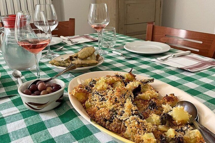 A table with a checkered tablecloth, a plate of food, a bowl of grapes, and wine glasses. 4