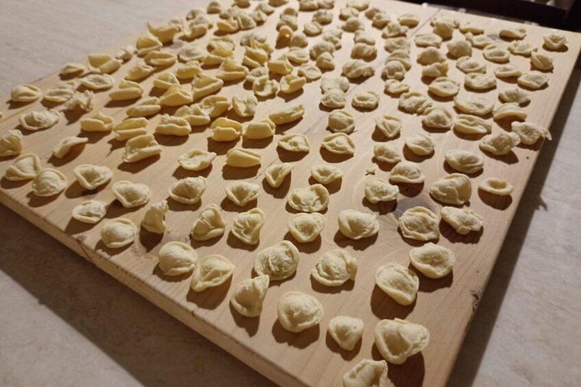 A wooden board with numerous small, round, dough-like objects arranged in rows. 3