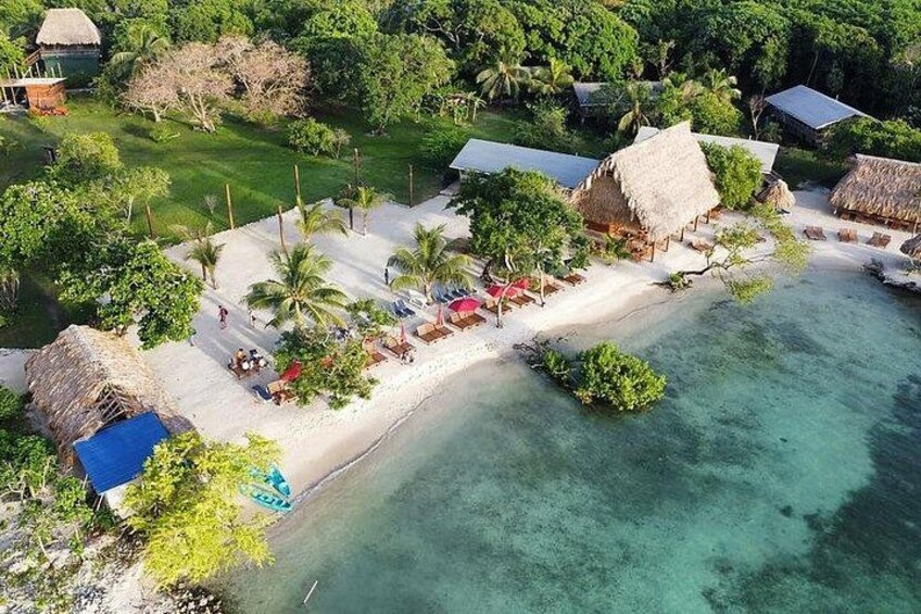 Una località balneare tropicale con capanne a tetto di paglia, palme e acque turchesi cristalline. 3