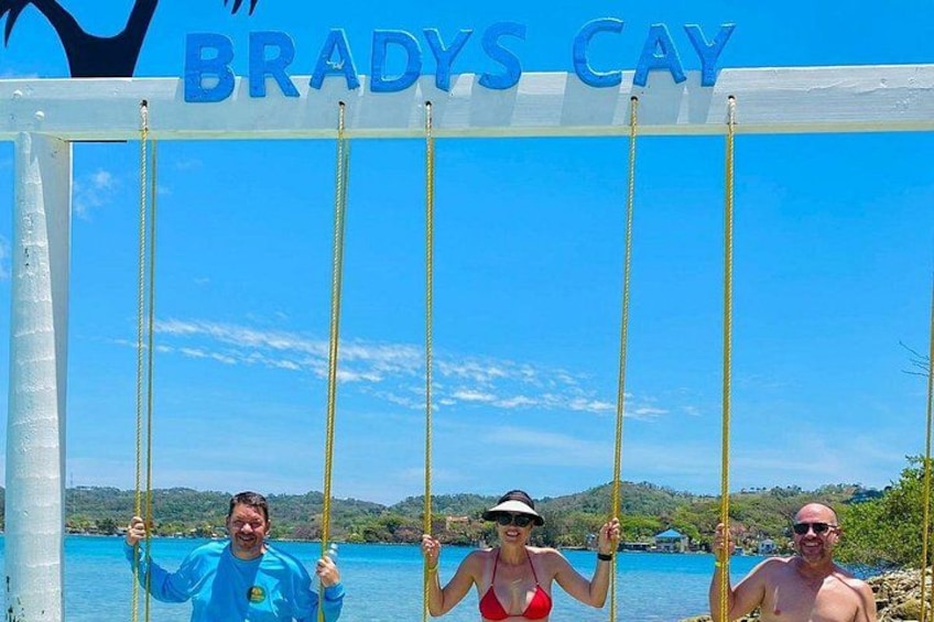 Tres personas en un columpio, con 'BRADYS CAY' escrito arriba. 4