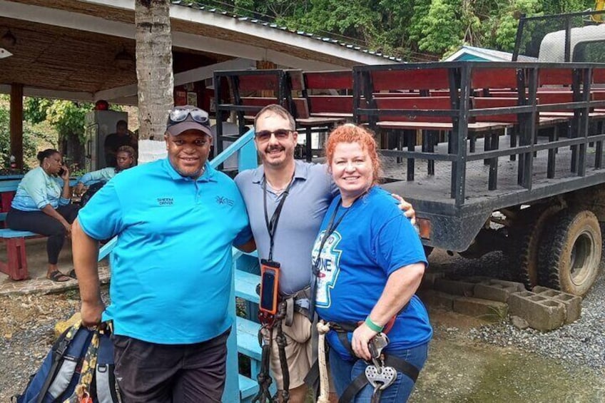 Three people standing in front of a truck with a covered area and benches in the background. 4