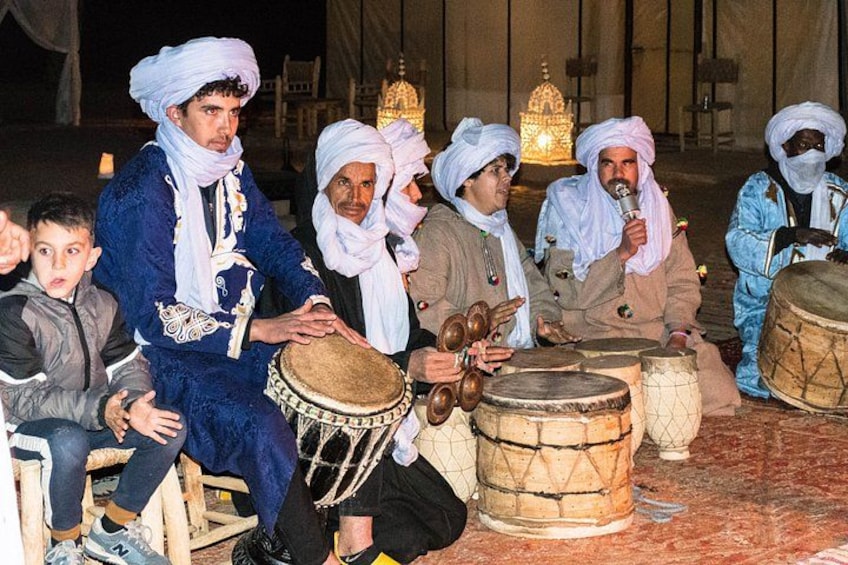 A group of people playing traditional drums in a dimly lit setting. 1