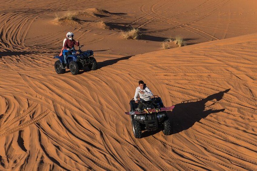 Two people riding quad bikes on a sandy dune landscape. 3