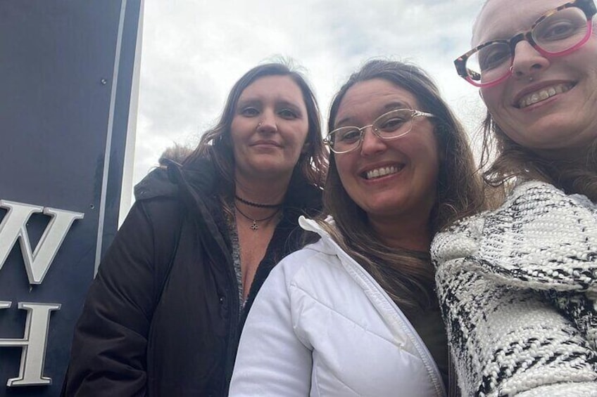 Drie personen staan voor een bord met letters. 2