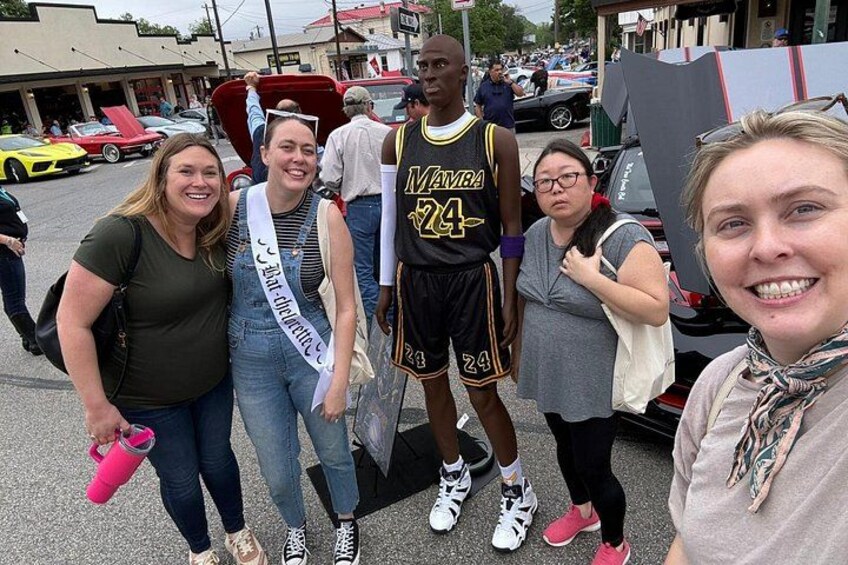 A group of people posing for a photo with a basketball player in a black and yellow uniform. 2