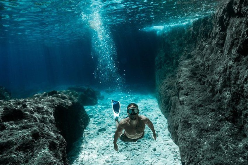 A diver underwater in a rocky crevice. 4