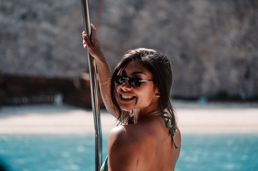 A person holding onto a pole by a body of water with a rocky shoreline in the background. 3