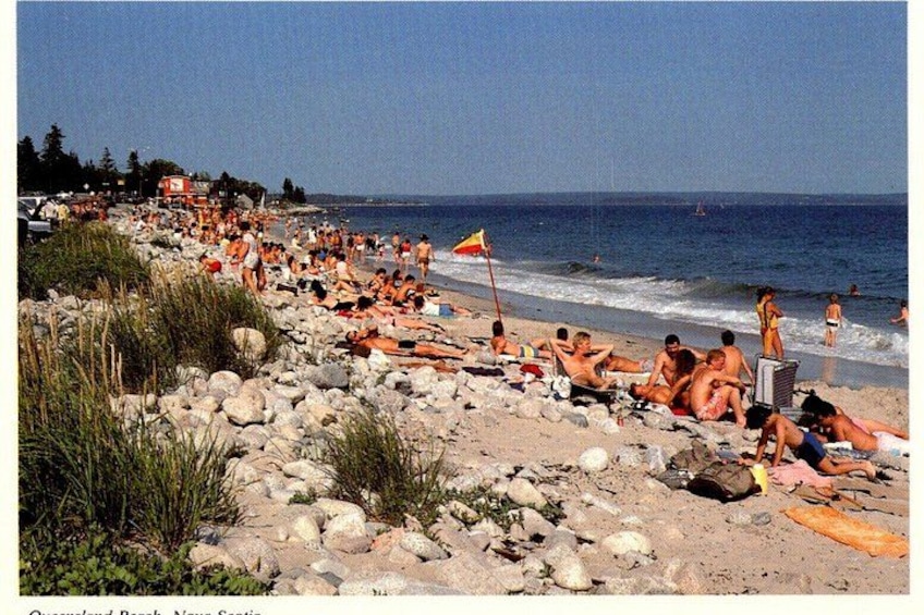 A crowded beach with people sunbathing and swimming. 4