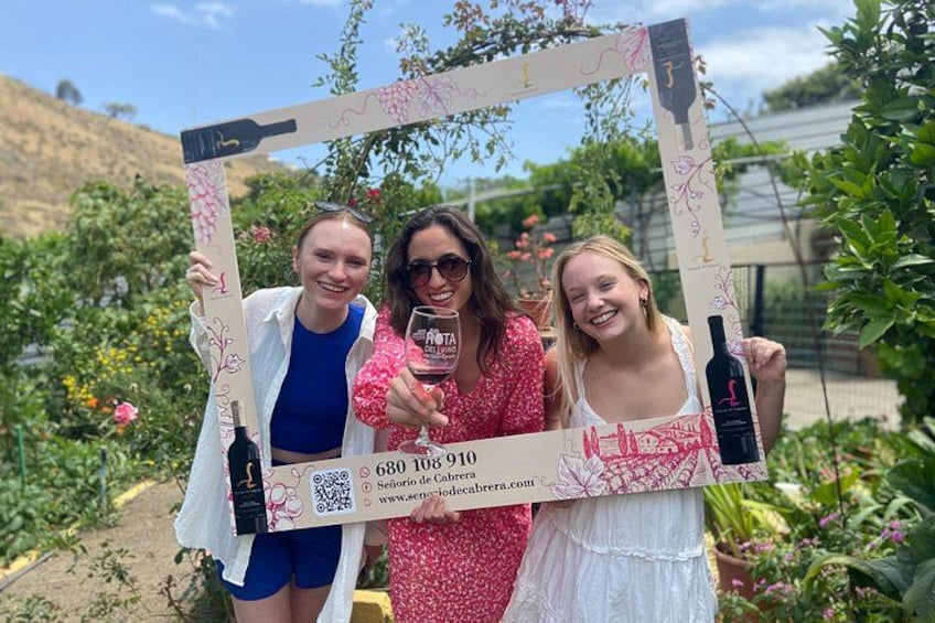 Three people standing in a garden with a decorative frame. 2