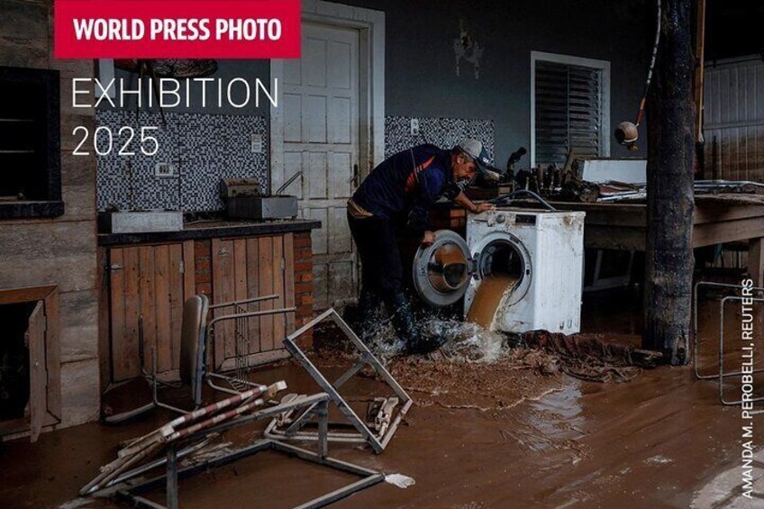 A flooded room with a person cleaning a washing machine. 3