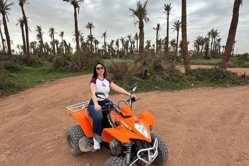 Iemand op een oranje quad rijdt door een landelijk gebied met palmbomen. 3