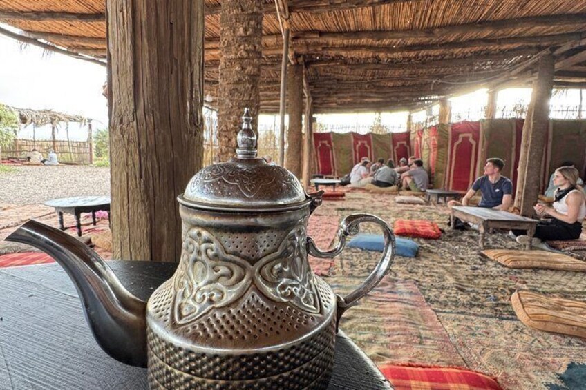 Een klassieke metalen theepot met ingewikkelde versieringen, op een geweven matje gezet. 5