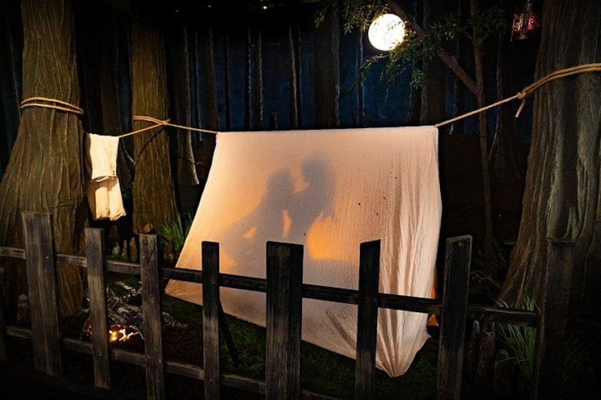 A wooden fence with a white cloth hanging on it, a tree, and a hanging light. 3