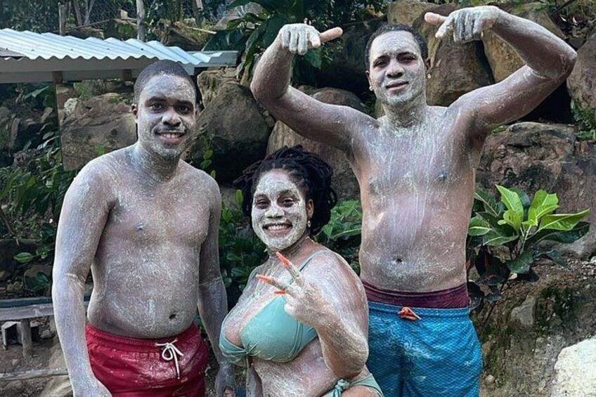 Three people with white powder on their bodies, standing in front of a rocky background. 2