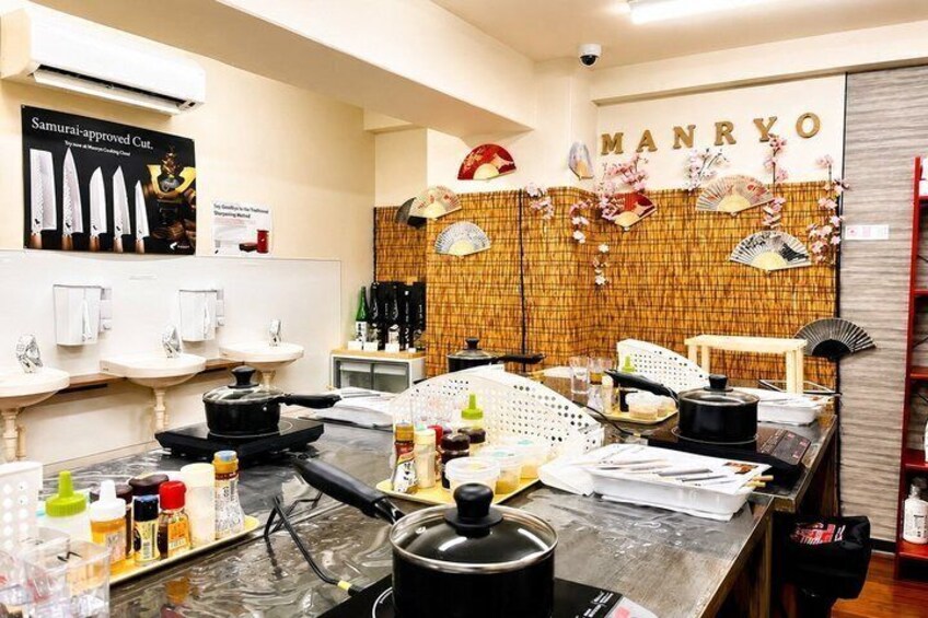 A kitchen with a counter, pots, bottles, and a wall with the name 'MANRYO'. 2