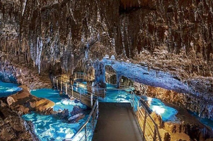 A cave with a water feature, a wooden walkway, and rocky formations. 1
