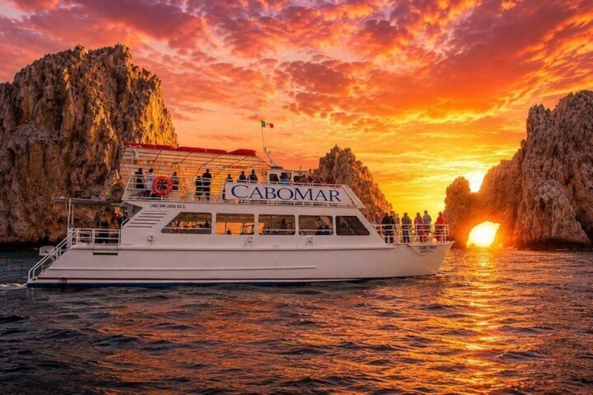 Un barco llamado CABOMAR navegando cerca de acantilados rocosos al atardecer. 1