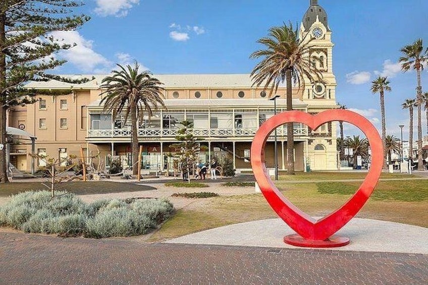 A heart-shaped sculpture in a plaza with a building in the background. 1