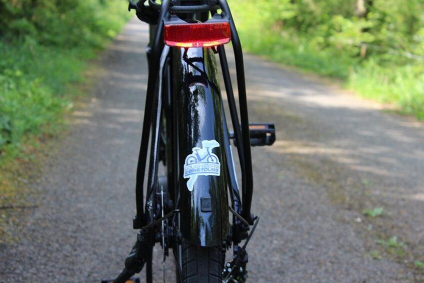 A bicycle with a red tail light and a sticker on the rear wheel. 3