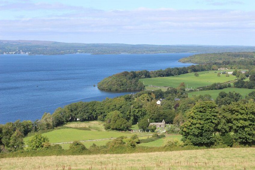 A coastal landscape with a large body of water, green fields, and a small building. 2