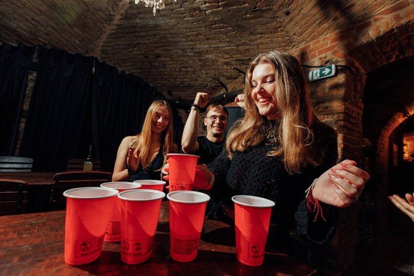 A group of people playing a game with red plastic cups at a brick-walled venue. 5