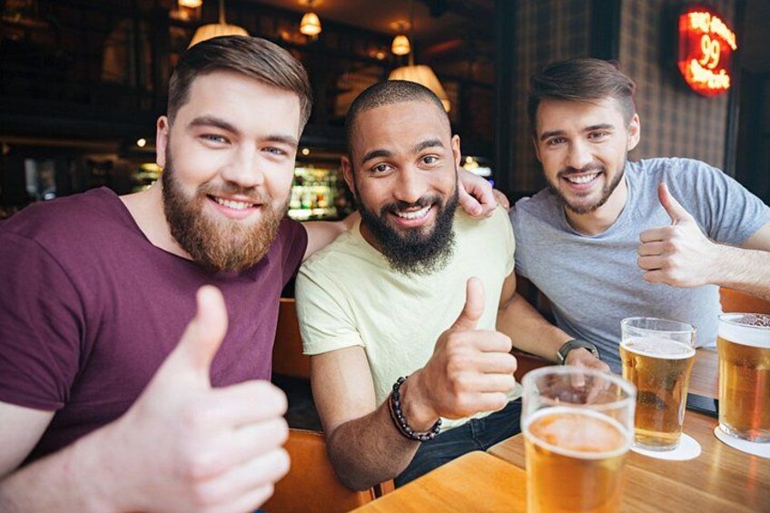 Three people sitting at a table with glasses of beer. 2