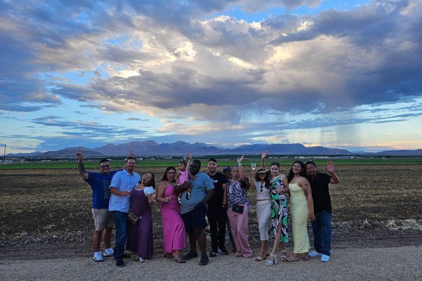 A group of people standing in a field with a mountainous landscape in the background. 2