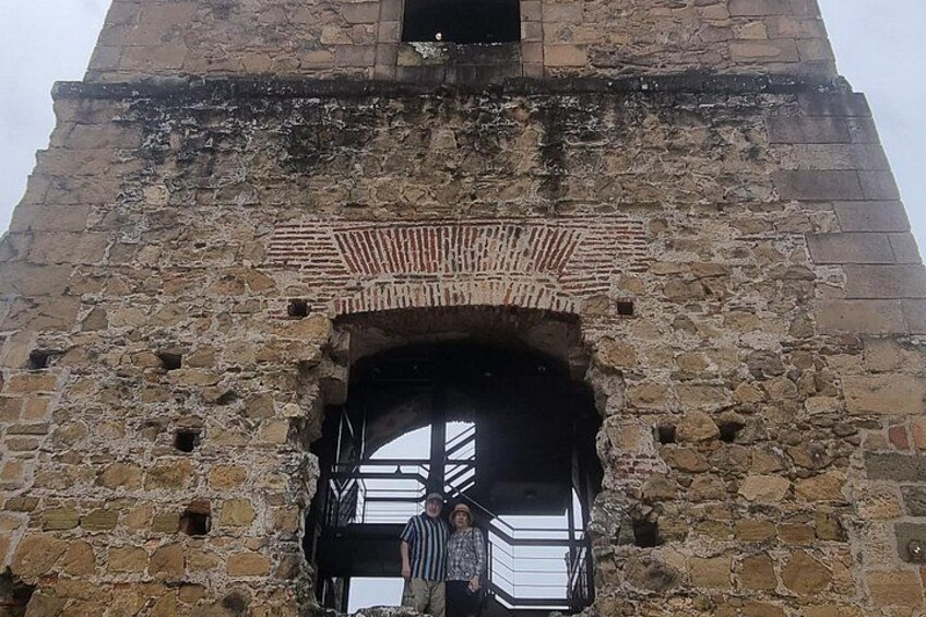 Een stenen toren met een grote bogenpoort en een metalen trap die omhoog leidt. 5