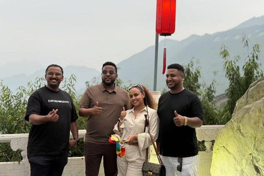 Four people standing on a terrace with a mountainous backdrop. 2